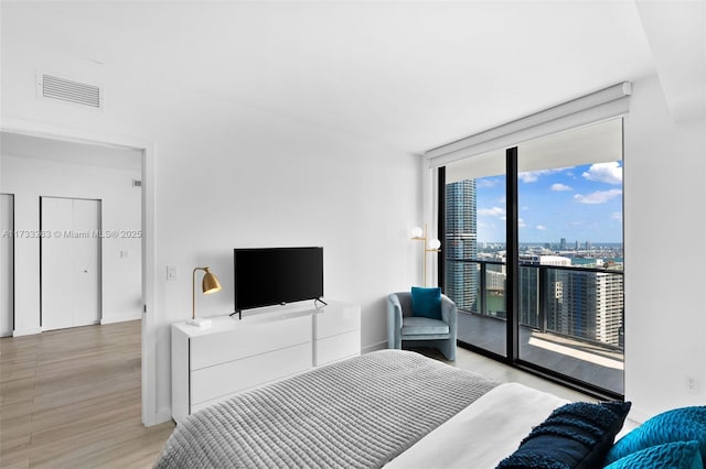 bedroom with expansive windows, access to exterior, and light wood-type flooring