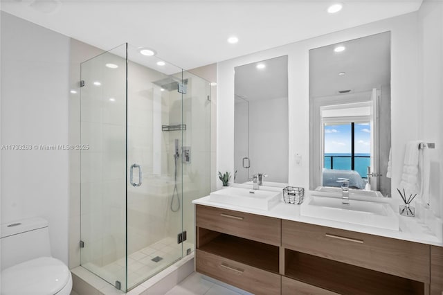 bathroom featuring a shower with door, vanity, a water view, and toilet