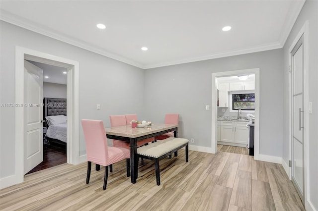 dining room featuring crown molding, sink, and light hardwood / wood-style floors