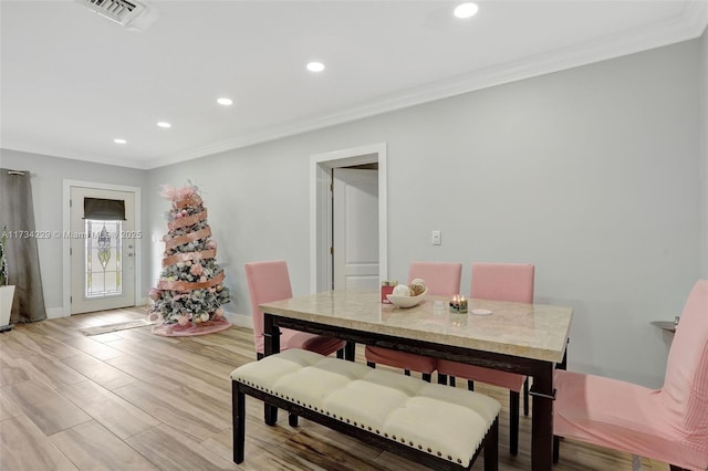 dining area with crown molding and light hardwood / wood-style flooring