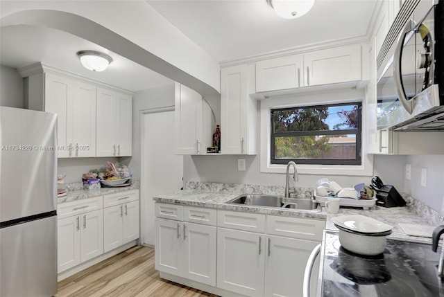 kitchen with white cabinetry, stainless steel appliances, light hardwood / wood-style floors, and light stone counters