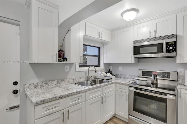 kitchen with light stone countertops, appliances with stainless steel finishes, sink, and white cabinets