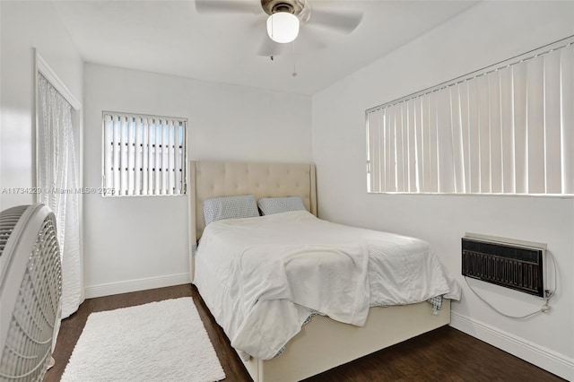 bedroom featuring dark hardwood / wood-style flooring, a wall unit AC, and ceiling fan