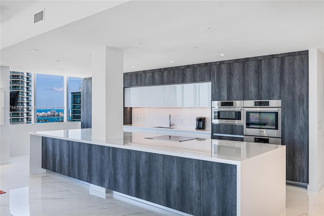 kitchen with a large island, sink, black electric stovetop, white cabinets, and stainless steel double oven