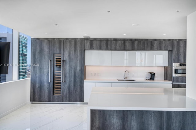 kitchen featuring sink, stainless steel oven, and white cabinets