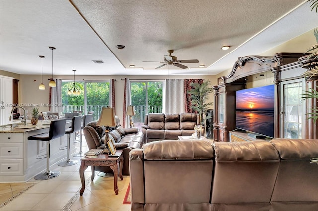 living room with light tile patterned floors, a textured ceiling, sink, and ceiling fan