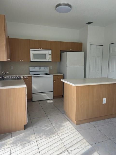 kitchen with sink, white appliances, light tile patterned floors, and a kitchen island