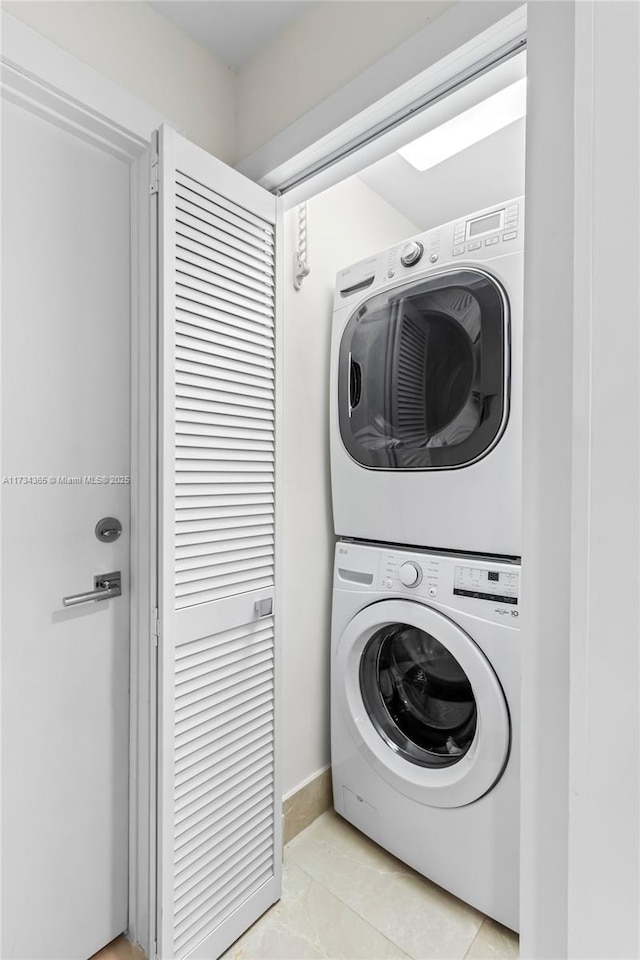 laundry area featuring stacked washer / drying machine and light tile patterned floors