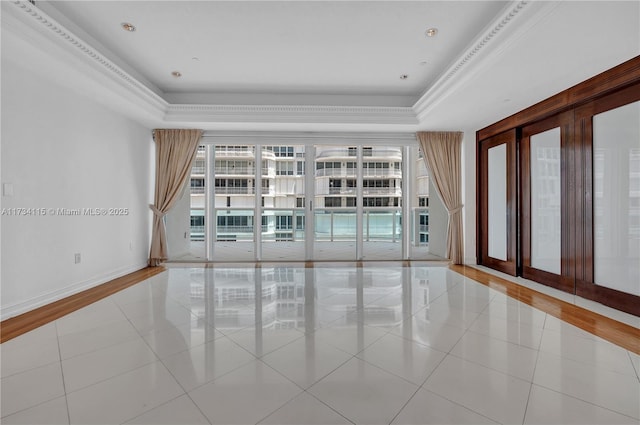 unfurnished room featuring a tray ceiling, ornamental molding, and light tile patterned flooring