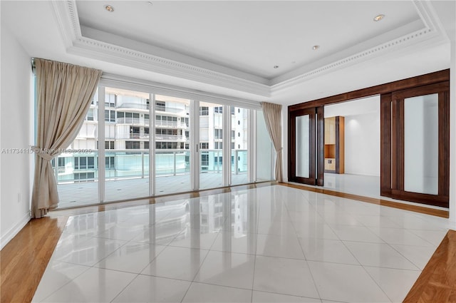 unfurnished room with a raised ceiling and light tile patterned floors