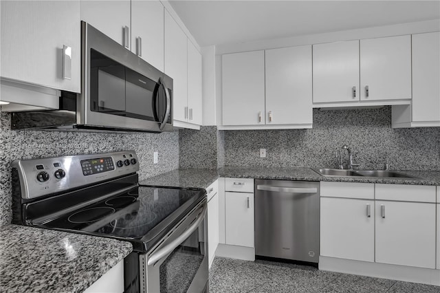 kitchen with appliances with stainless steel finishes, sink, white cabinets, and dark stone counters