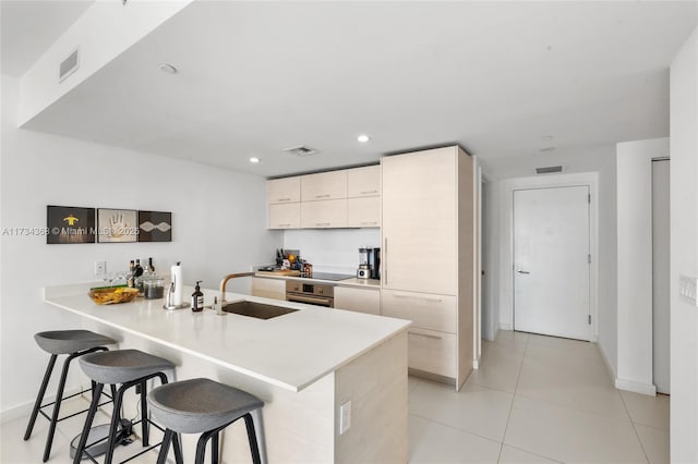 kitchen with sink, a breakfast bar area, stainless steel oven, black electric cooktop, and kitchen peninsula