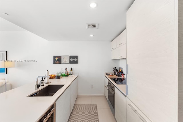 kitchen with sink, light tile patterned floors, black electric cooktop, oven, and white cabinets