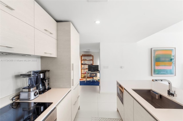 kitchen with sink, light tile patterned floors, white cabinets, and black electric stovetop