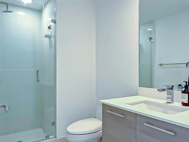 bathroom with vanity, a shower with shower door, and toilet