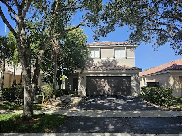 traditional home featuring concrete driveway, a tile roof, an attached garage, and stucco siding