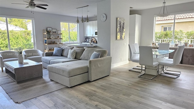 living room with ceiling fan, sink, and light hardwood / wood-style floors