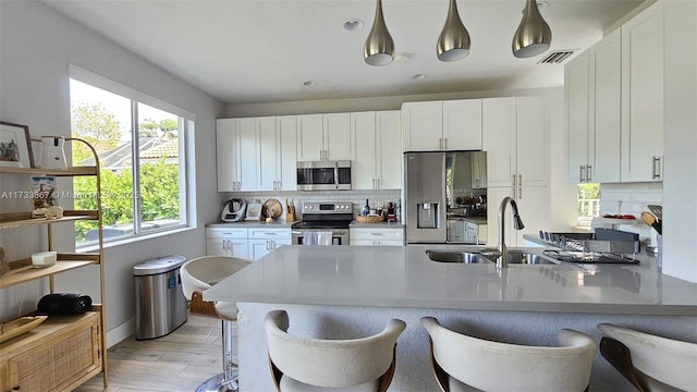 kitchen with stainless steel appliances, white cabinetry, a sink, and visible vents