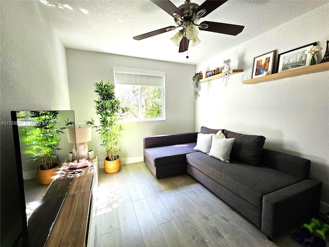 living area with light wood finished floors, baseboards, a textured ceiling, and a textured wall