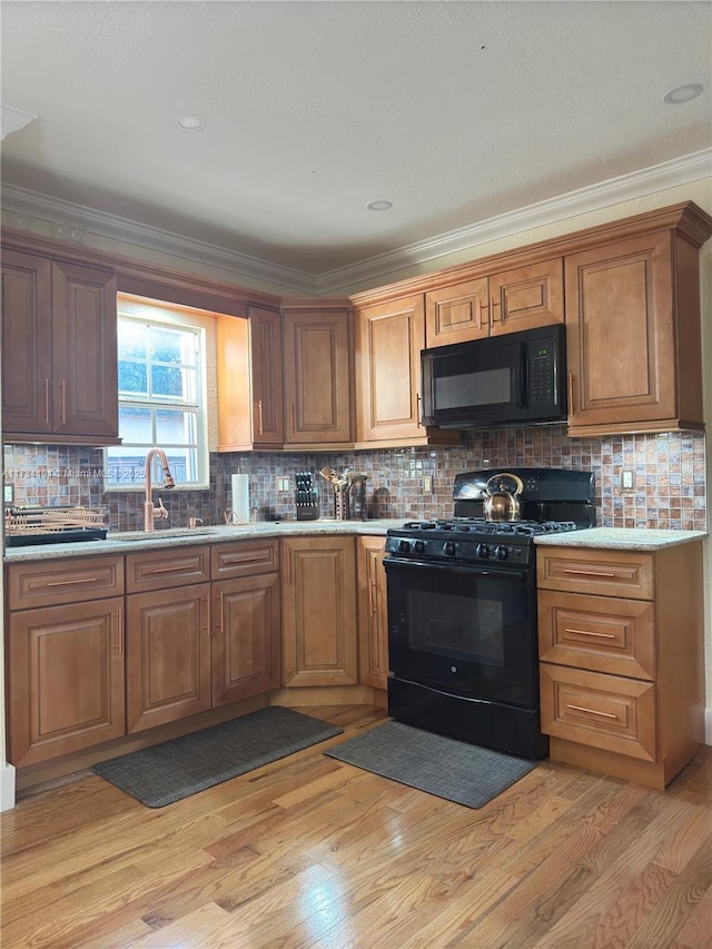 kitchen featuring light wood-type flooring, crown molding, sink, and black appliances