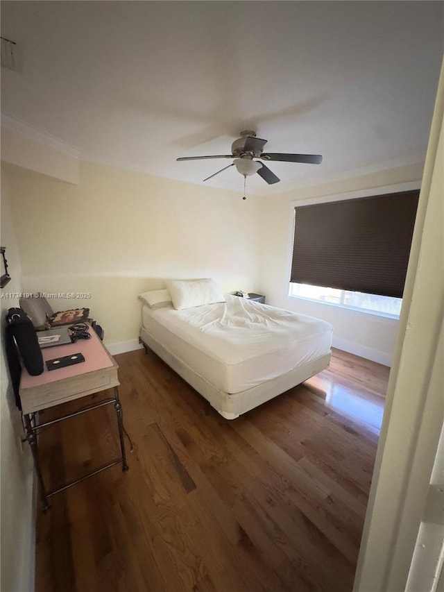 bedroom with crown molding, dark wood-type flooring, and ceiling fan