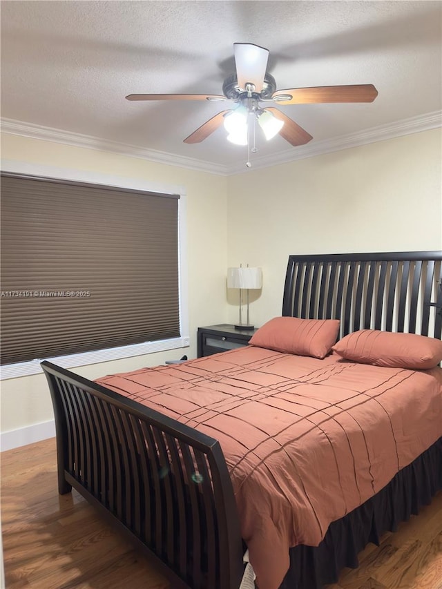 bedroom with hardwood / wood-style floors, a textured ceiling, ornamental molding, and ceiling fan