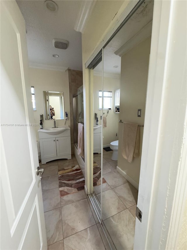 bathroom with walk in shower, vanity, crown molding, and toilet