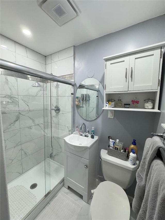 bathroom featuring vanity, a shower with door, and toilet