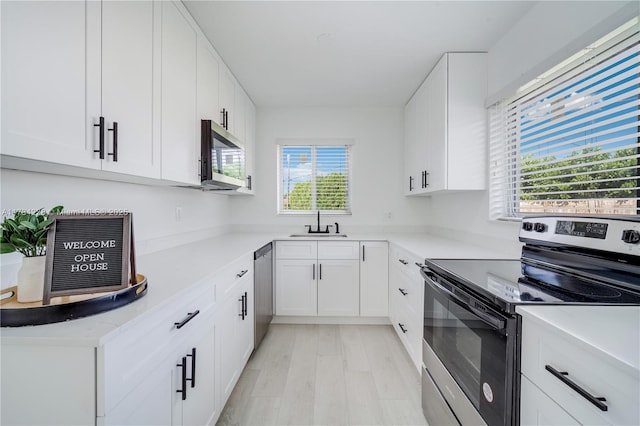 kitchen with light countertops, appliances with stainless steel finishes, light wood-style floors, white cabinetry, and a sink