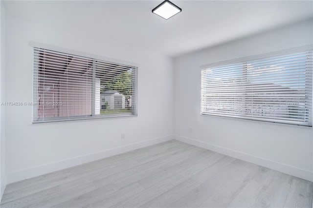 unfurnished room featuring baseboards and light wood-type flooring