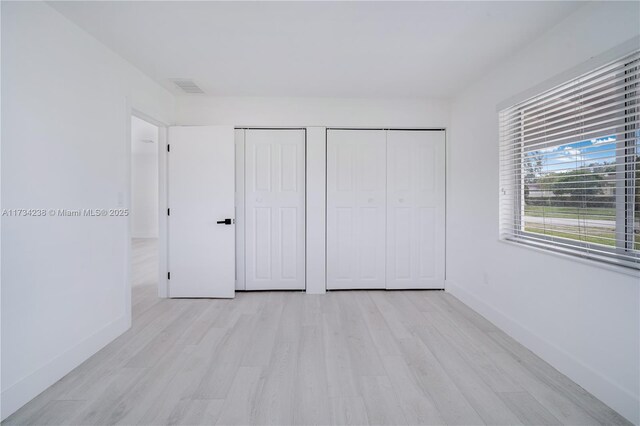 unfurnished bedroom with light wood-type flooring and a closet