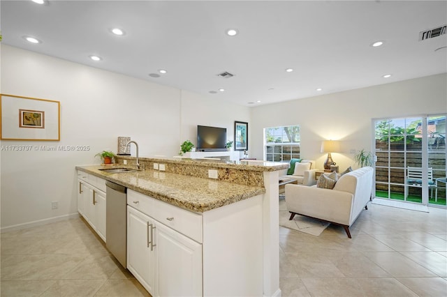 kitchen with sink, light tile patterned floors, white cabinetry, light stone counters, and stainless steel dishwasher