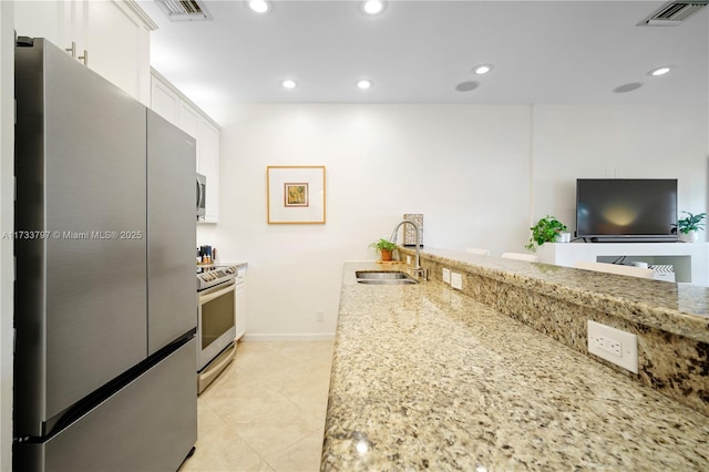 kitchen featuring light stone countertops, appliances with stainless steel finishes, sink, and white cabinets