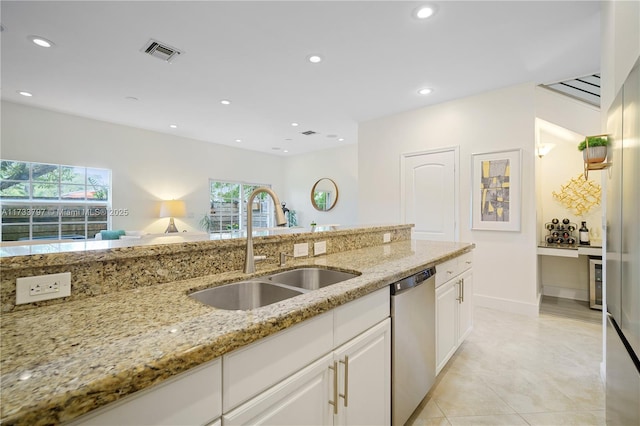 kitchen with sink, light tile patterned floors, white cabinetry, light stone counters, and stainless steel dishwasher