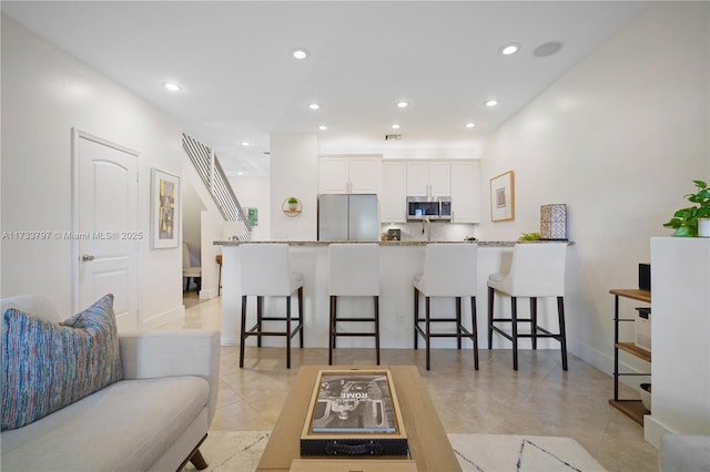 kitchen featuring kitchen peninsula, a breakfast bar, white cabinets, and appliances with stainless steel finishes