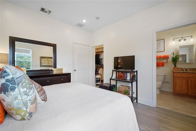 bedroom with ensuite bath, wood-type flooring, sink, and a closet