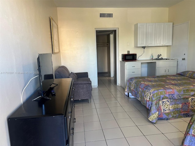 bedroom featuring sink, light tile patterned floors, and a closet