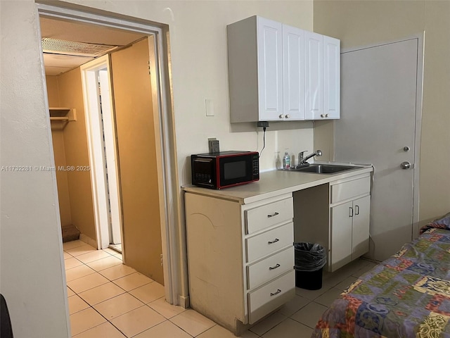 kitchen with sink, light tile patterned floors, and white cabinets