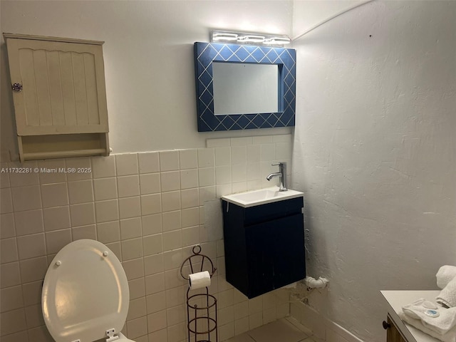 bathroom with vanity, toilet, and tile walls