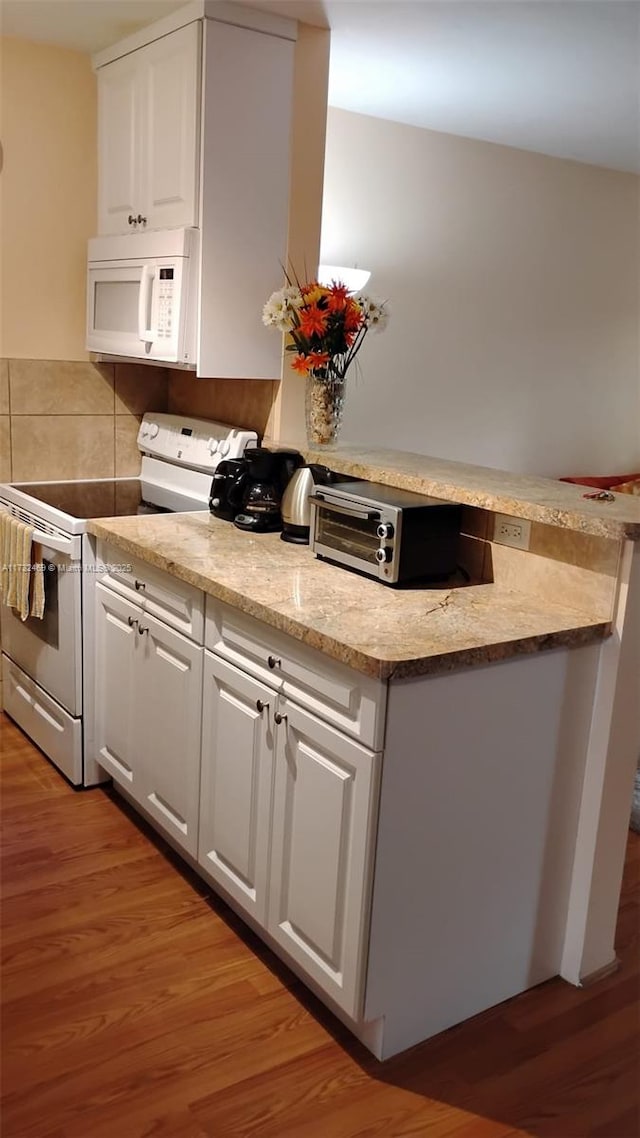 kitchen featuring white appliances, light stone countertops, light wood-type flooring, and white cabinets