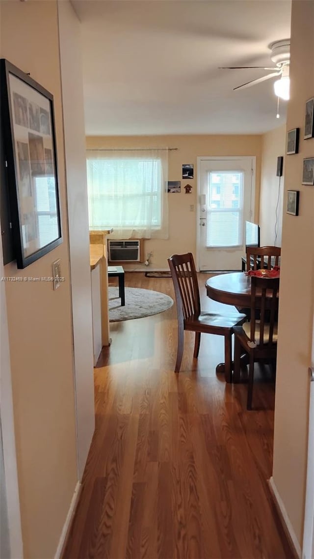 dining area with ceiling fan, hardwood / wood-style floors, and an AC wall unit