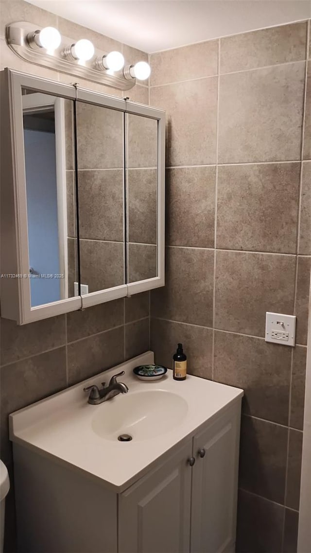 bathroom with vanity, tile walls, and backsplash