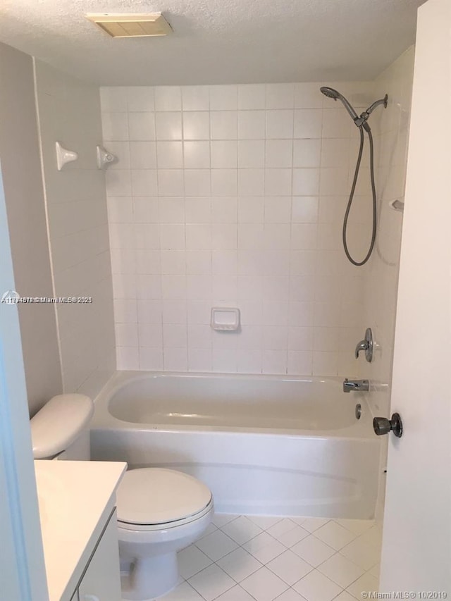 full bathroom with tiled shower / bath combo, tile patterned flooring, toilet, a textured ceiling, and vanity