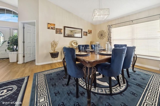 dining room with lofted ceiling, wood finished floors, baseboards, and a chandelier