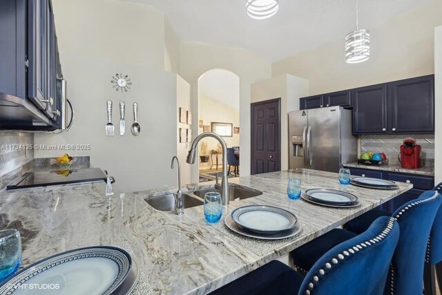 kitchen with stainless steel appliances, light stone countertops, hanging light fixtures, and decorative backsplash