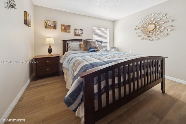 bedroom with wood finished floors, baseboards, and a textured ceiling