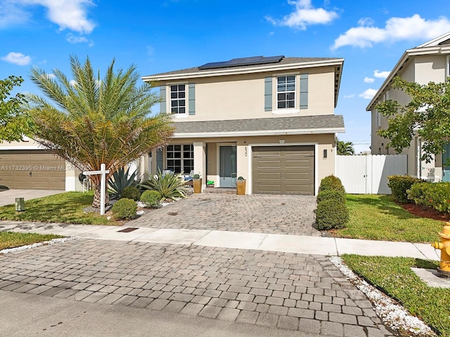 view of front property with a garage, a front yard, and solar panels