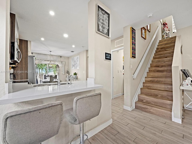 kitchen with stainless steel appliances, sink, a kitchen bar, and kitchen peninsula