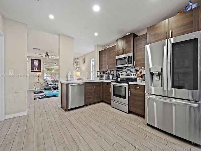 kitchen with sink, backsplash, kitchen peninsula, stainless steel appliances, and light wood-type flooring