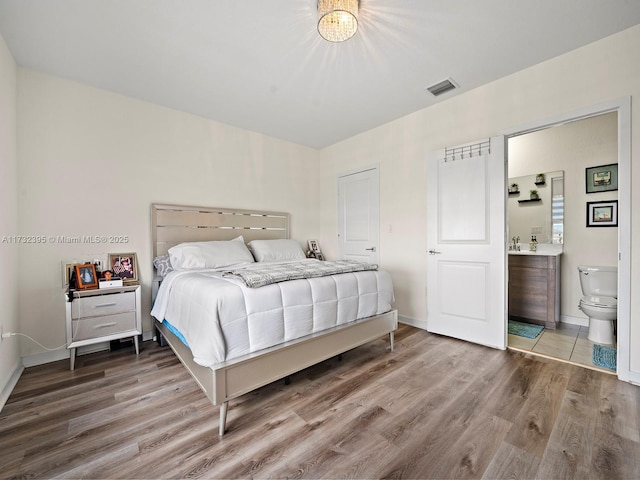 bedroom with hardwood / wood-style flooring and ensuite bathroom